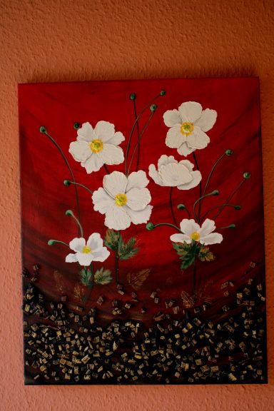 Weiße Blumen auf rotem Hintergrund, mit grünen Stängeln und schwarzem Boden.